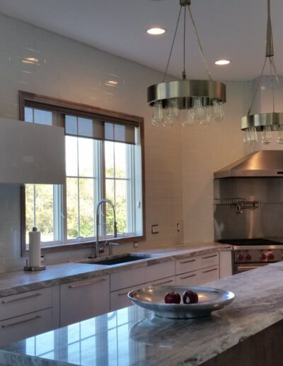 Modern kitchen with stainless steel appliances, marble countertops, and pendant lighting.