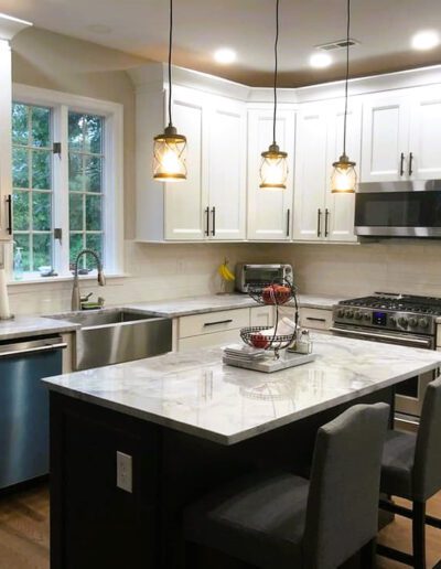 A modern kitchen with white cabinetry, stainless steel appliances, and pendant lighting over a central island.