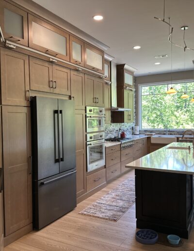 Modern kitchen interior with wooden cabinetry, stainless steel appliances, and an island with seating area.