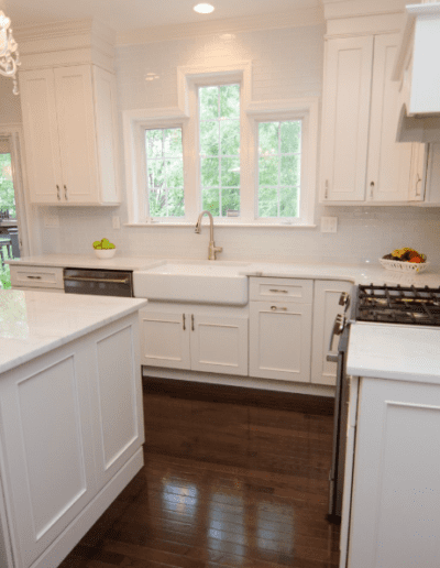 Bright, modern kitchen with white cabinetry, marble countertops, and stainless steel appliances.