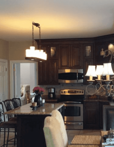 A cozy kitchen interior featuring wooden cabinetry, stainless steel appliances, and pendant lighting.